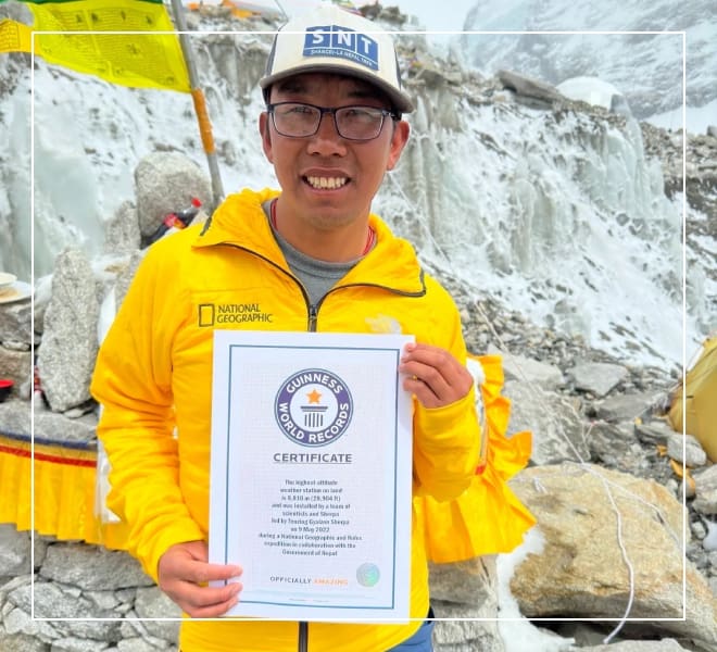 A man holding up a certificate in front of a rock wall.