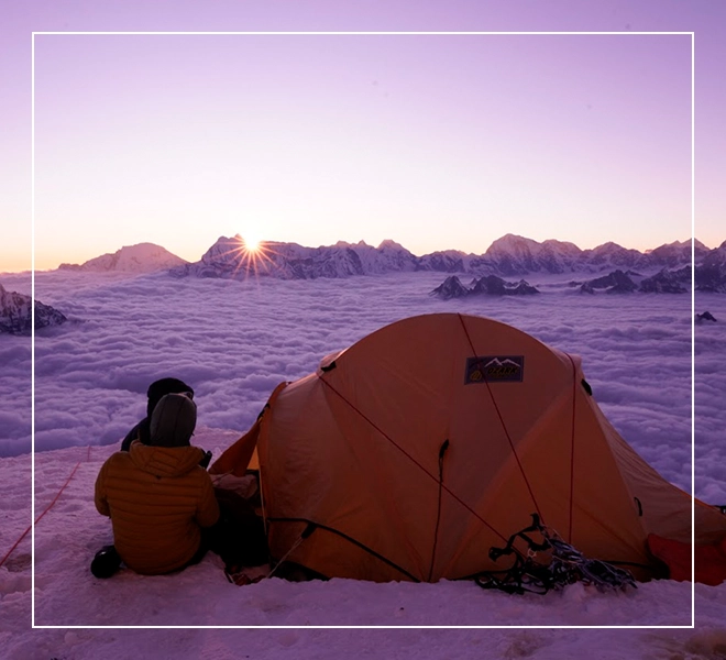 A person sitting in front of an orange tent.