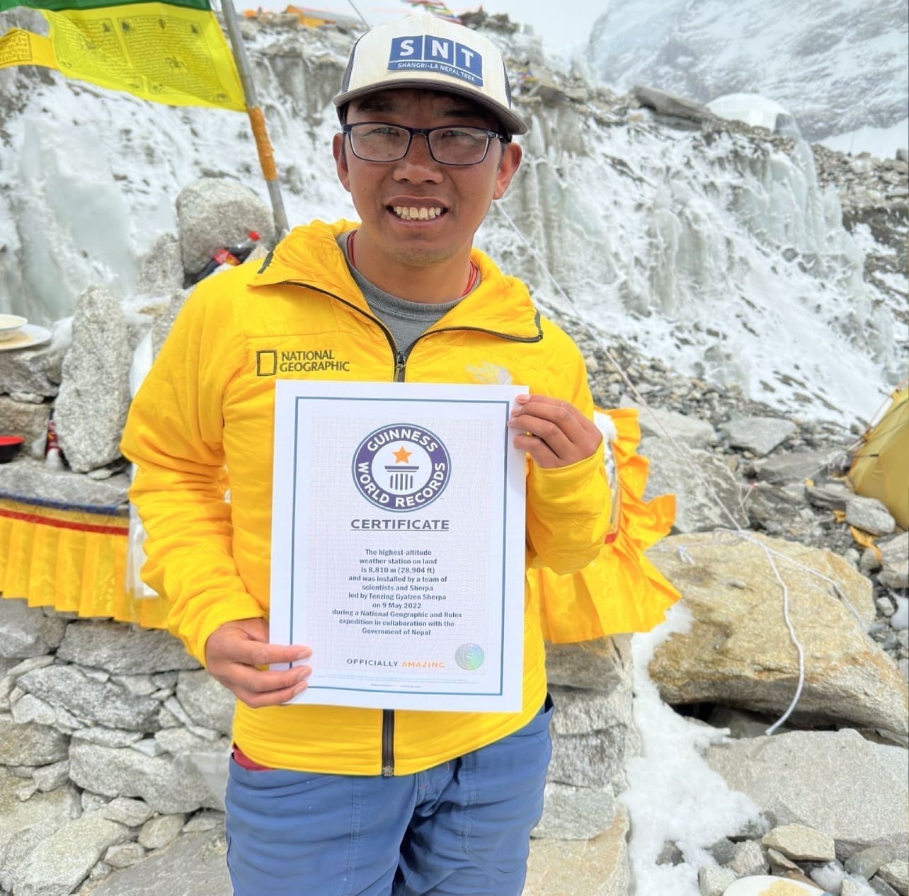 A man holding up a certificate in front of some rocks.