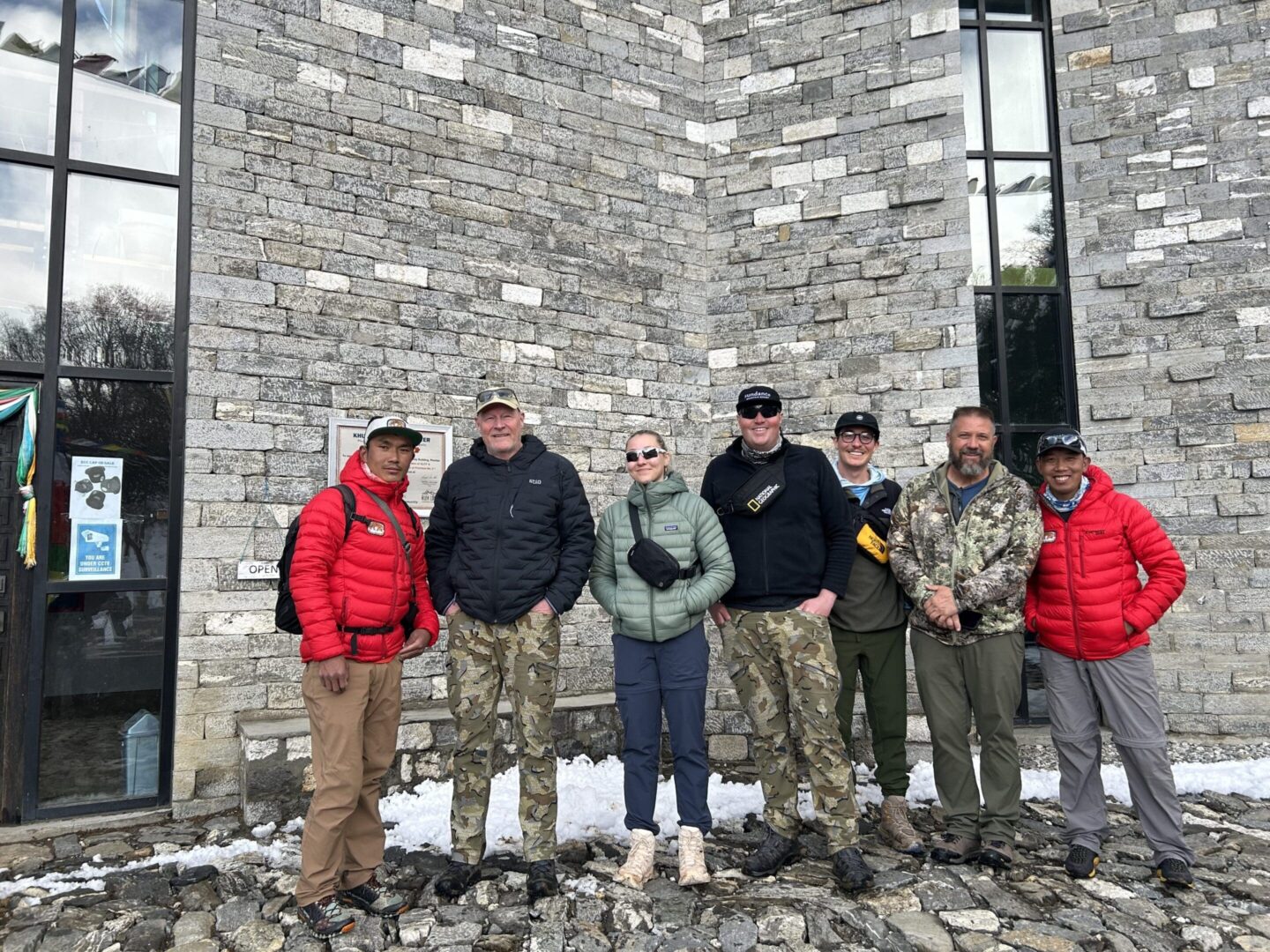 A group of people standing in front of a stone wall.