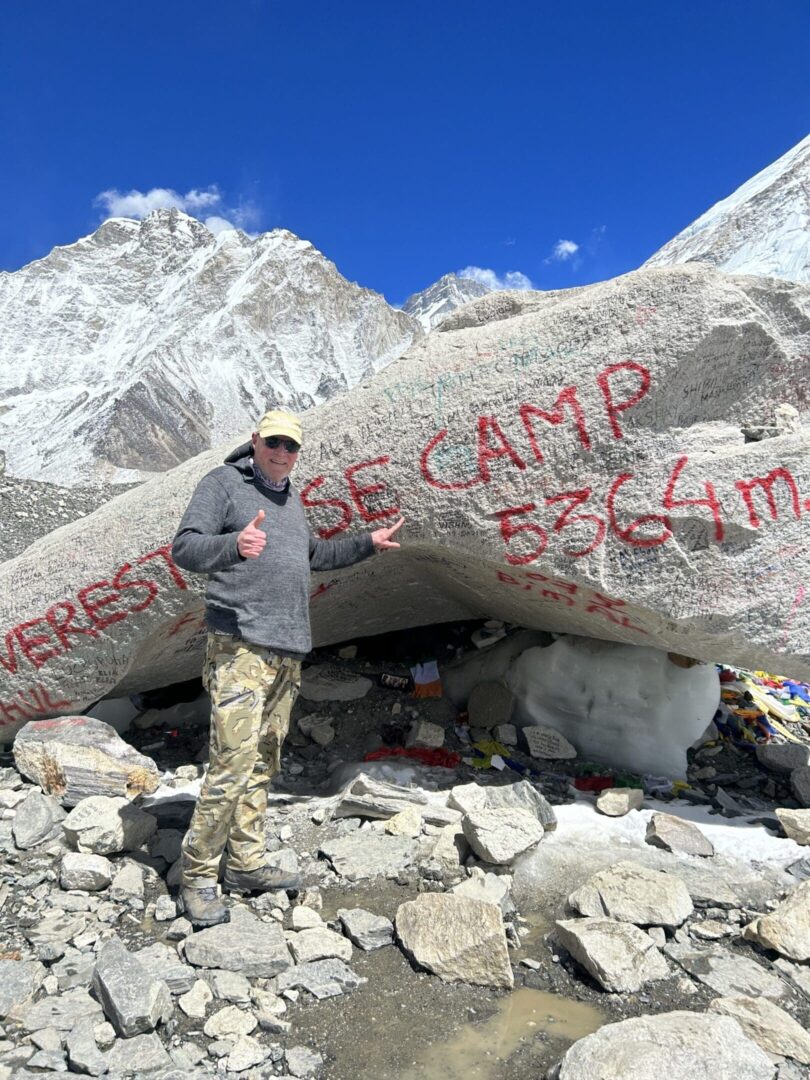 A man standing in front of a large rock.