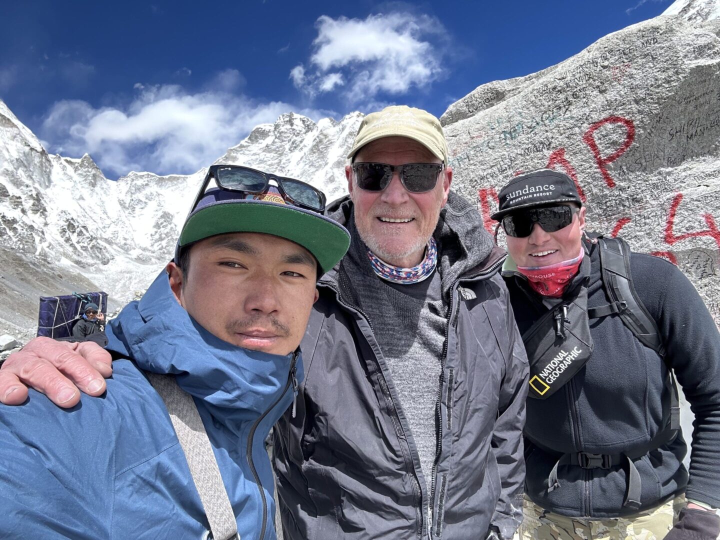 Three people standing in front of a mountain.