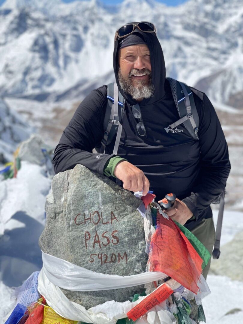 A man in black jacket holding onto rock